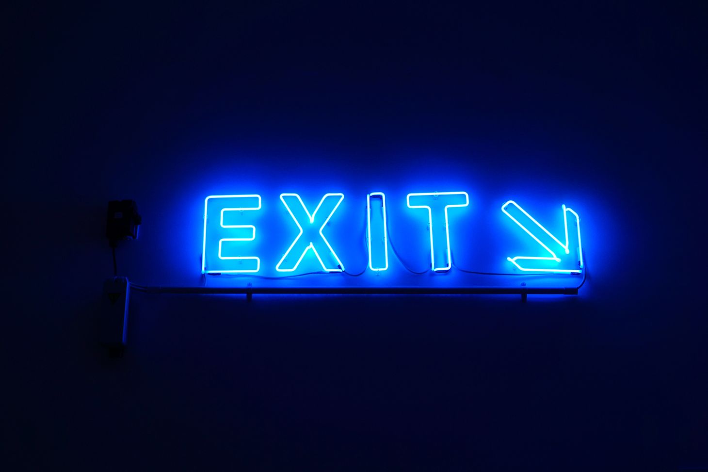 Blue neon letters spell EXIT with an arrow pointing to the right